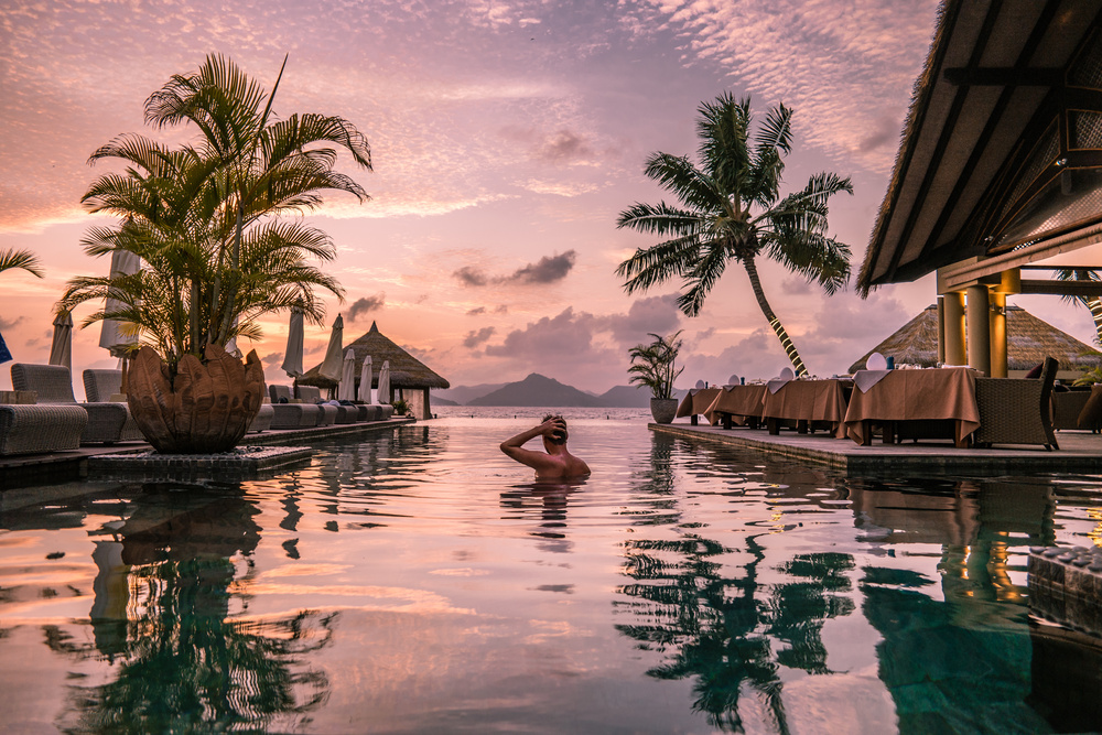 Un homme dans la piscine avec vue sur la mer, Les Seychelles