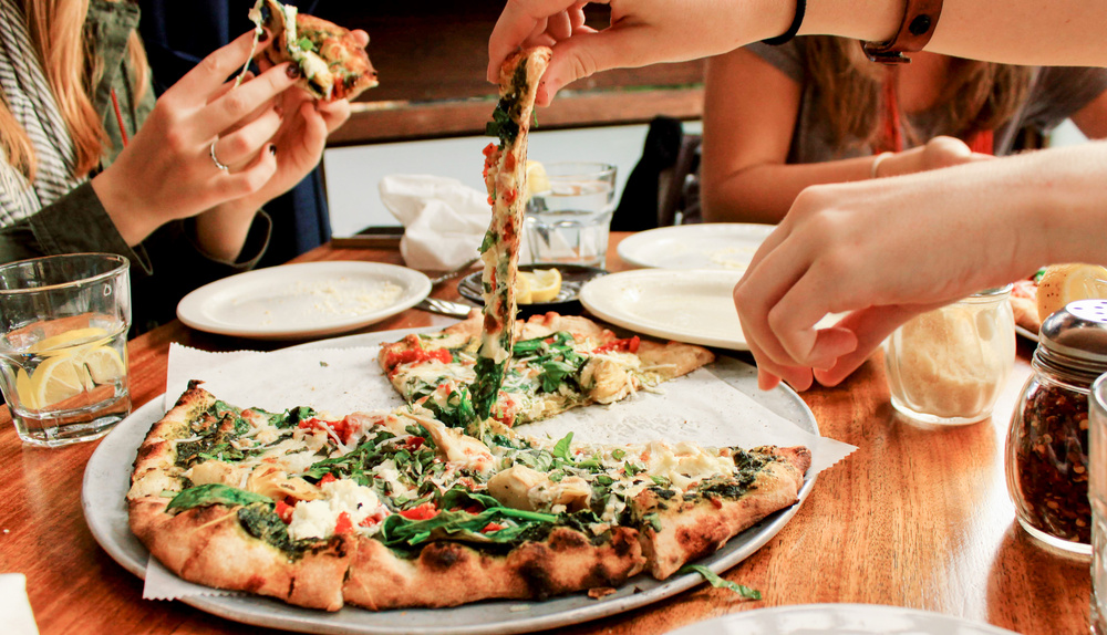Amis partageant une pizza au restaurant
